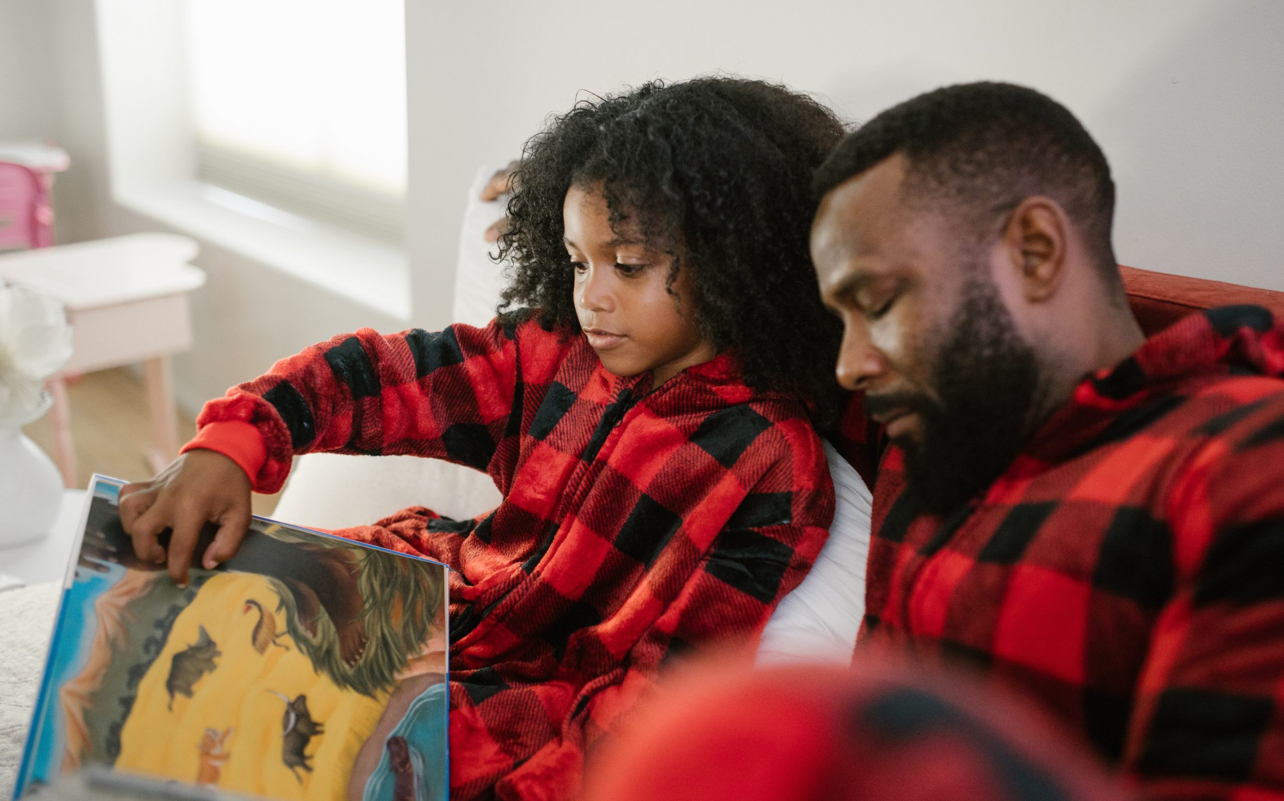 une enfant et un adulte qui lisent un livre en pyjama