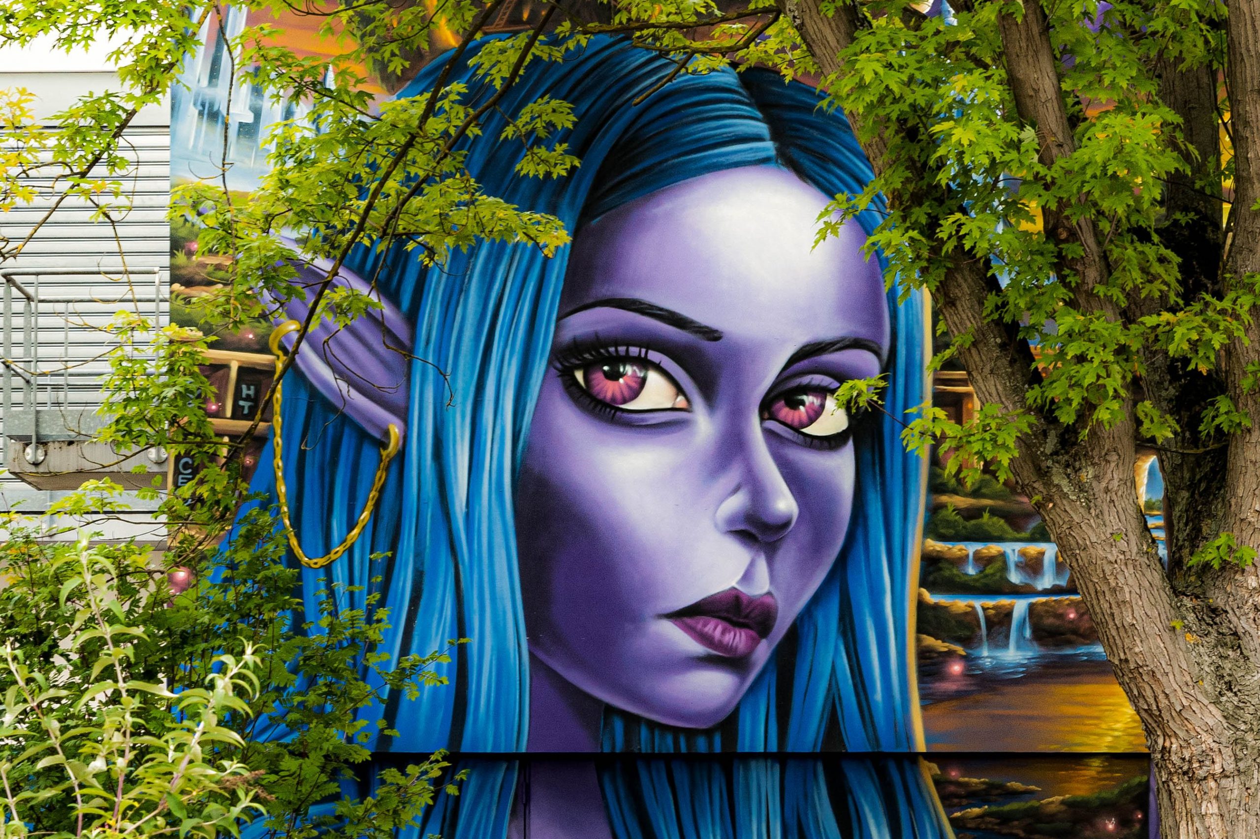 Oeuvre de Street Art représentant une femme à la peau violette, aux cheveux bleus et avec des oreilles "d'elfes"